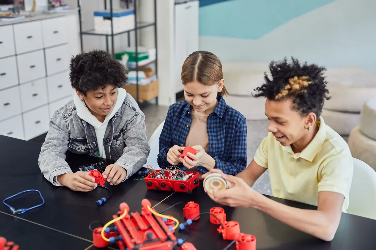 Three students assembling robotics components together